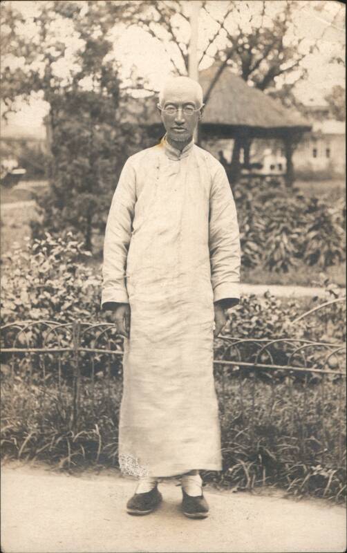 Chinese Man in traditional long gown, glasses, garden setting China