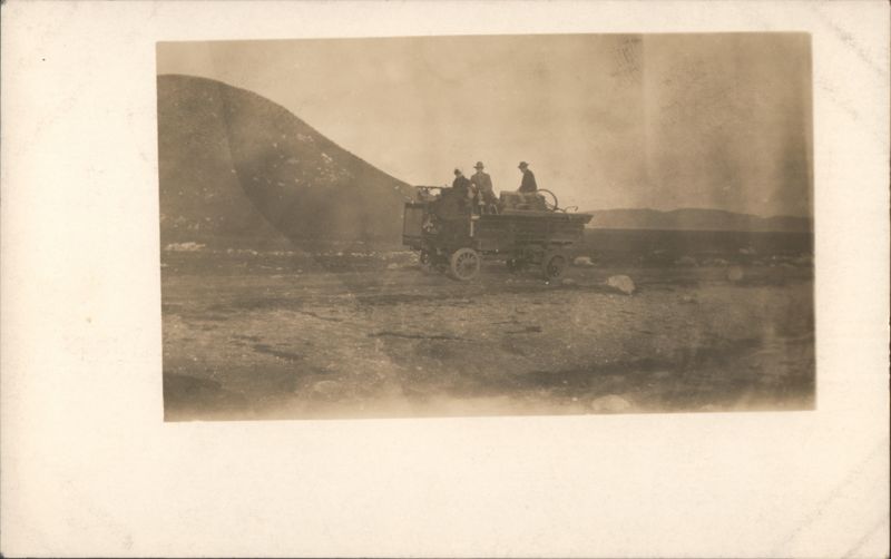 Men on vehicle in barren mountainous landscape