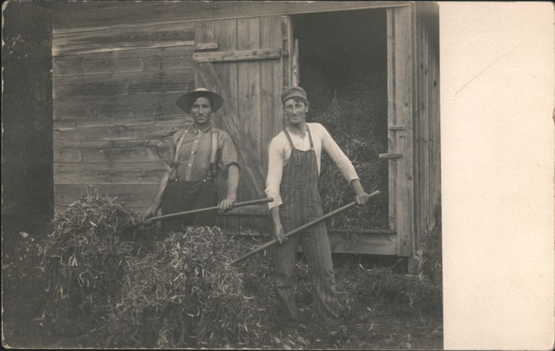 Two Farmers with Rakes and Hay by Wooden Barn