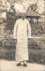 Chinese Man in traditional long gown, glasses, garden setting Postcard