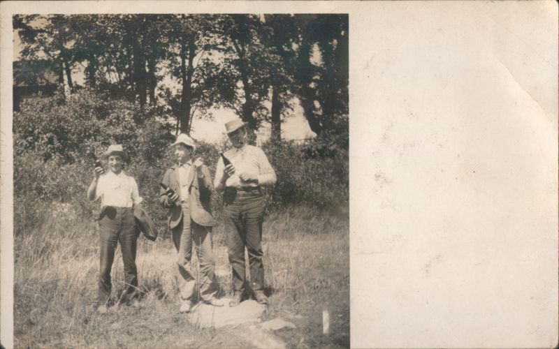 Three Men Holding Bottles in a Field