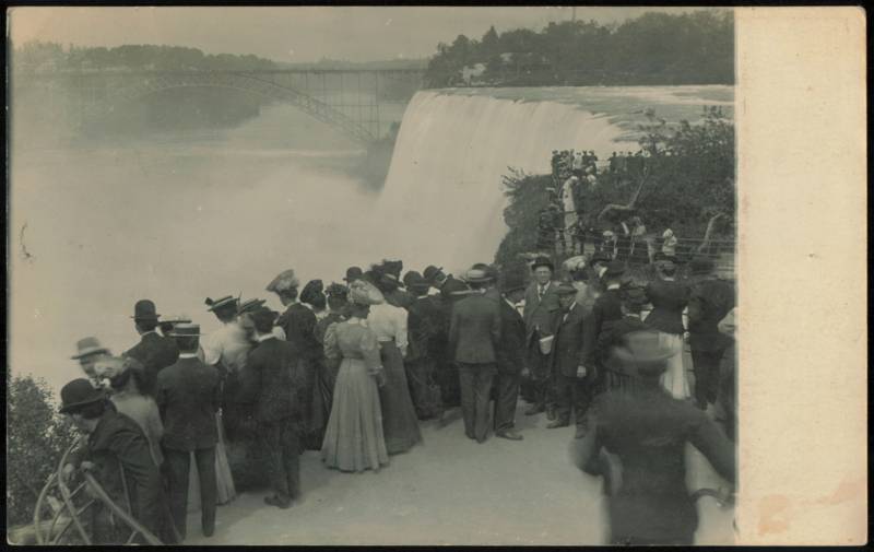 Tourists at Niagara Falls with Upper Steel Arch Bridge New York