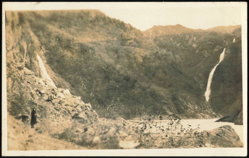 Person Standing Near Two Waterfalls in Mountain Landscape