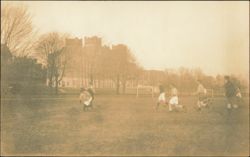 Men Playing Soccer on Field with Castle-like Building Postcard