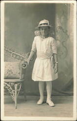 Young Girl in Summer Dress and Hat beside Wicker Settee Postcard