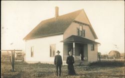 Couple Standing in Front of Rural Frame House Postcard