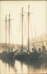 Two Wooden Schooners Docked by Waterfront Building Postcard