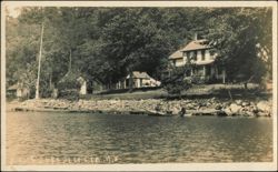 Houses along Rocky Shoreline with Rowboat Postcard