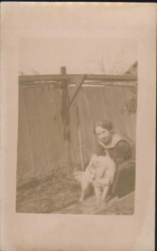 Young Woman with White Dog Outdoors by Wooden Fence