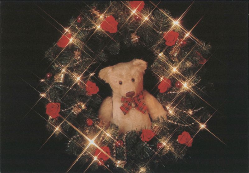 Teddy Bear in Christmas Wreath with Red Roses and Sparkling Lights