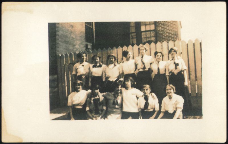 Group of 12 Young Adults in Uniforms by Wooden Fence