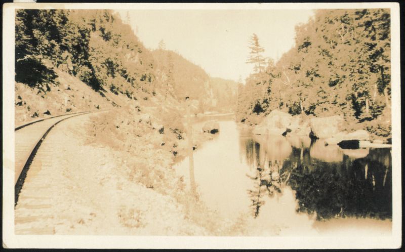 Railroad Tracks along River in Mountainous Landscape