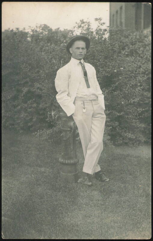 Young Man in Suit and Hat Leaning on Post Men