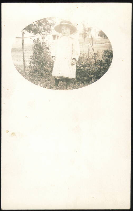 Young Child in Hat and Coat with Man in Background
