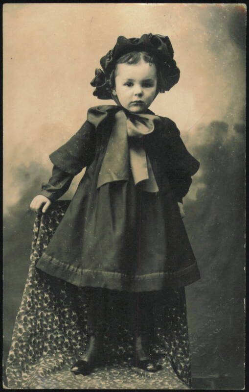 Young Child in Ruffled Hat and Dark Dress Studio Portrait