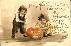 Two children (boy and girl) playing with a Jack-o-lantern Halloween Postcard Postcard