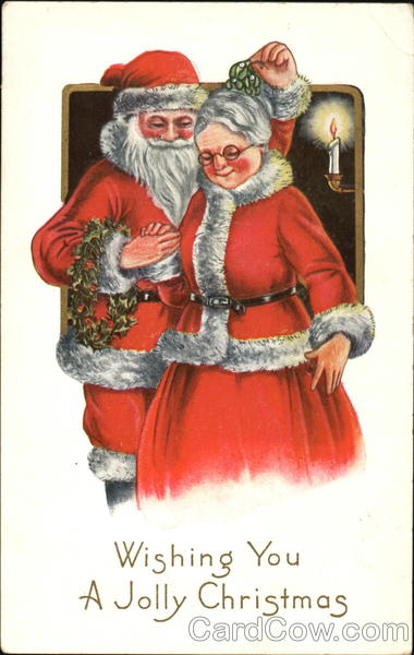 Santa holds mistletoe over Mrs. Claus' head while holding a wreath