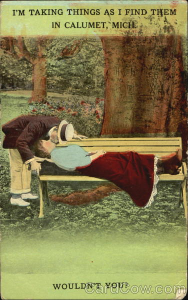 Man kissing woman in red skirt as she lies on a bench