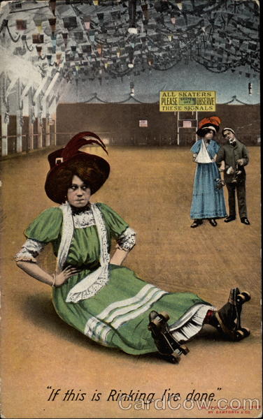 Woman in a long dress and wearing roller skates sits on a rink floor