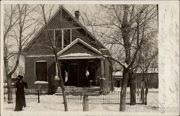 Three women in snow in front of house