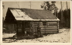 Man with gun outside log cabin Postcard