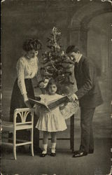 Man, Woman and Girl in front of Christmas Tree Postcard