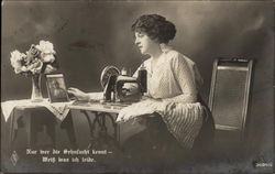 Woman at Sewing Machine Gazing Fondly at Photograph of Man in Uniform Postcard