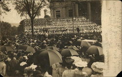 People sitting in stands, others with umbrellas Postcard