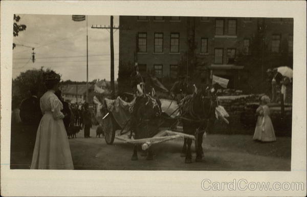 A horse-drawn carriage in a early 20th century parade.