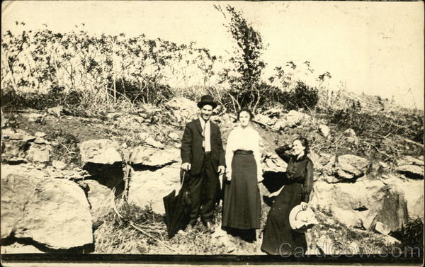 Outdoor photo of men and women near a rock outcrop, early 20th century