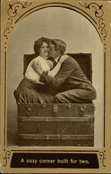 Woman and Man Kissing while Sitting in a Traveling Trunk Postcard