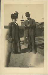 Couple Standing by Wire Fence, Woman with Large Hat Postcard