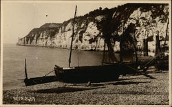Boats on the Shore with a Rocky Cliff and Water in the Background Boats on the Shore with a Rocky Cliff and Water in the Background