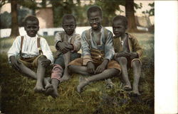 Four Smiling African American Boys Sitting On The Grass Four Smiling African American Boys Sitting On The Grass