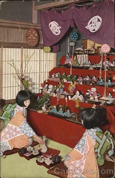 Two Asian Women Kneeling on Floor in Front of Large Doll Display