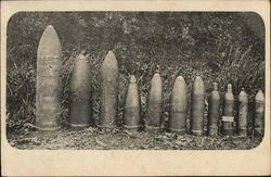 Various sized munitions standing in a line on end Postcard