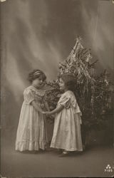 girls holding hands in front of a Christmas tree Postcard