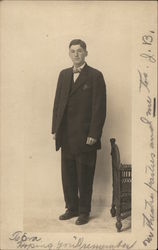 Young Man in Dark Suit Standing Near Furniture Young Man in Dark Suit Standing Near Furniture