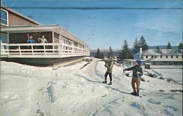 Two Skiers on a Slope Calling to Two People on Porch of an Inn