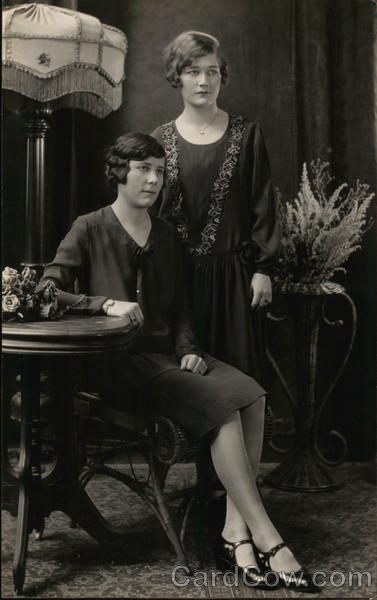 Two Ladies, One Seated, One Standing Near Lamp and Table Benton Harbor