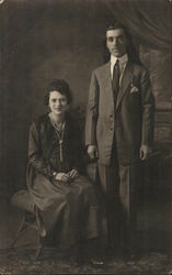 Man in Suit Standing Next to Seated Woman Postcard