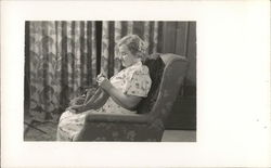 A Woman Sitting in a Chair Knitting Postcard