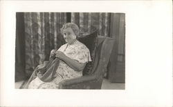 A Woman Sitting in a Chair Knitting Postcard