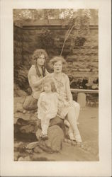 One Little Girl Seated on Rocks with Two Older Girls Postcard