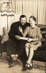 Man, Woman Seated on Sofa Sharing Box of Chocolates Postcard