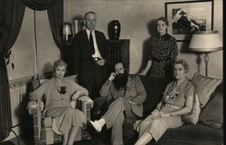 Three women and two men in a living room. Postcard