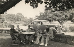 Group Seated at Table Outdoors with Dog (Collie) Postcard