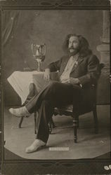 A Man Sitting Next to a Table Postcard