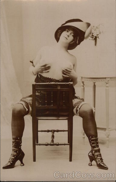 Topless Female in Garters, High-Heeled Boots, Seated and Holding Breasts
