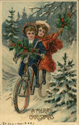 A young girl and boy ride a bicycle through the snow carrying holly branches Postcard